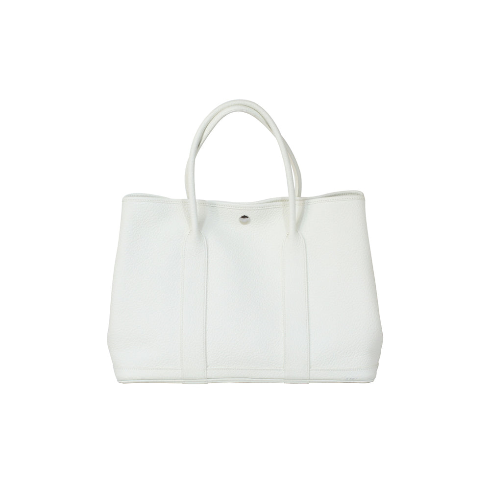 The handbag features two rolled leather handles.