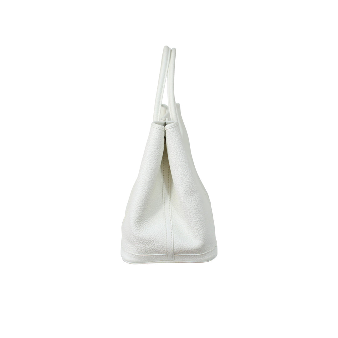 The side of the handbag features a snap button closure to fasten the bag.