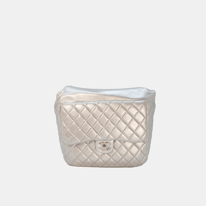 A silver metallic lambskin Chanel backpack with a quilted design and silver hardware, featuring a flap pocket and chain straps.