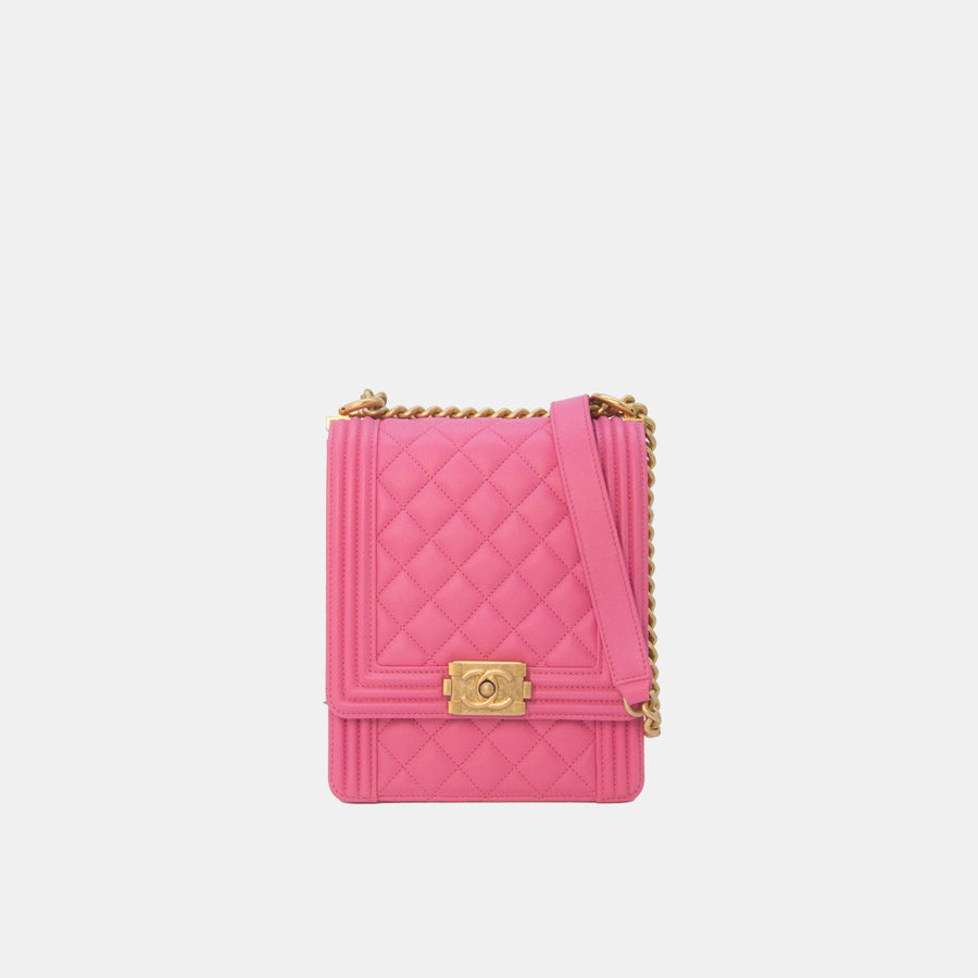 A vertical pink Chanel North South Boy Flap Bag with gold hardware, featuring the brand's interlocking CC logo, quilted leather, and a chain strap.