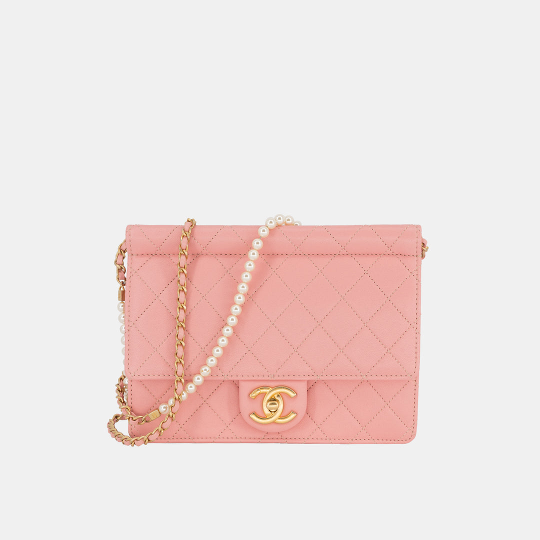 A pink Chanel Pearl Chain Flap Bag with a gold-toned chain cross-body strap with white pearls.