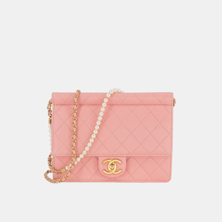 A pink Chanel Pearl Chain Flap Bag with a gold-toned chain cross-body strap with white pearls.