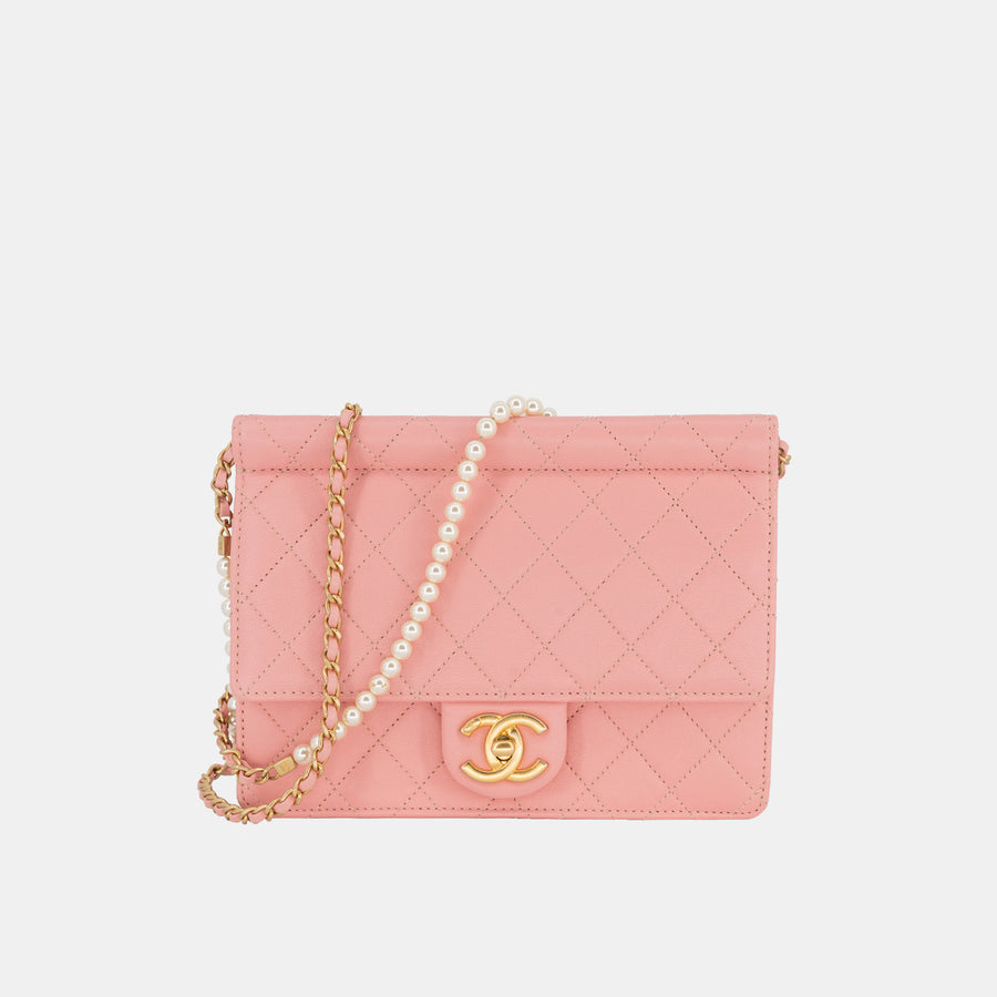 A pink Chanel Pearl Chain Flap Bag with a gold-toned chain cross-body strap with white pearls.