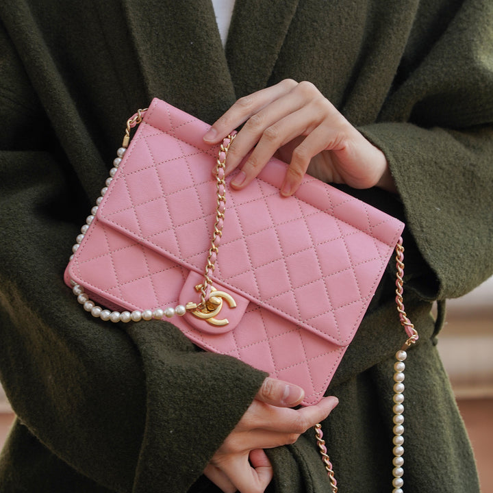Model carrying the Chanel pink flap bag with pearl chain.