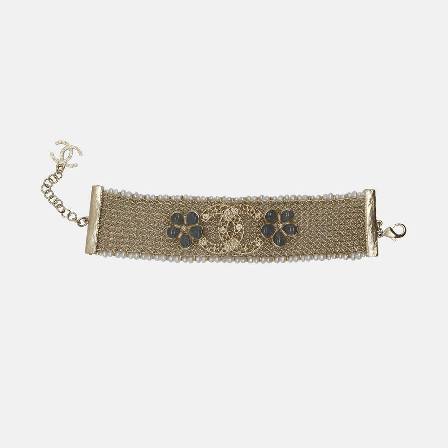 A gold-tone Chanel mesh bracelet featuring a double C logo and floral designs.