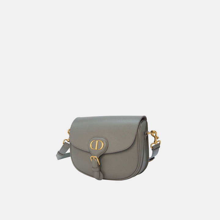 This crossbody bag features a magnetic buckle closure with CD hardware.