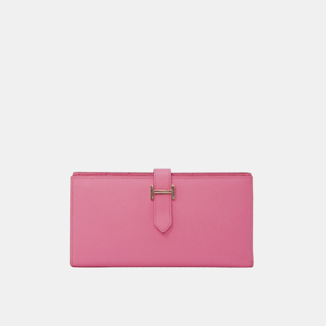 A pink Hermes Bearn wallet with silver hardware, featuring the iconic Hermes 'H' logo on the strap.