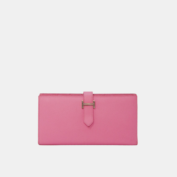 A pink Hermes Bearn wallet with silver hardware, featuring the iconic Hermes 'H' logo on the strap.