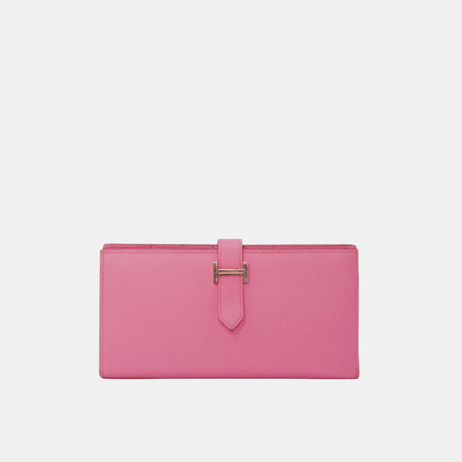 A pink Hermes Bearn wallet with silver hardware, featuring the iconic Hermes 'H' logo on the strap.
