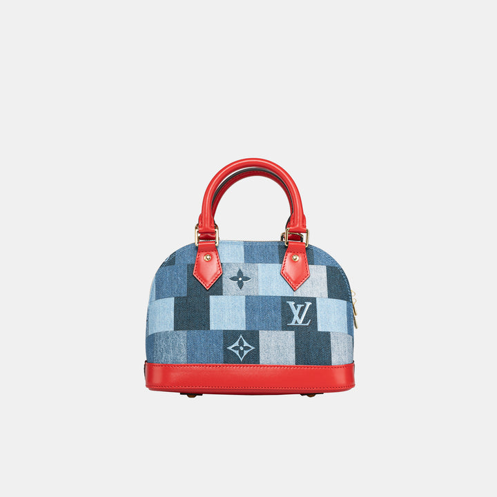 Louis Vuitton Alma BB handbag with a patchwork denim design featuring the brand's Damier monogram motif, red leather handles and base, and a zip closure.