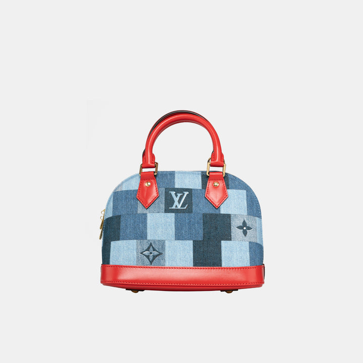 This bag features two red rolled leather top handles and leather bottom.