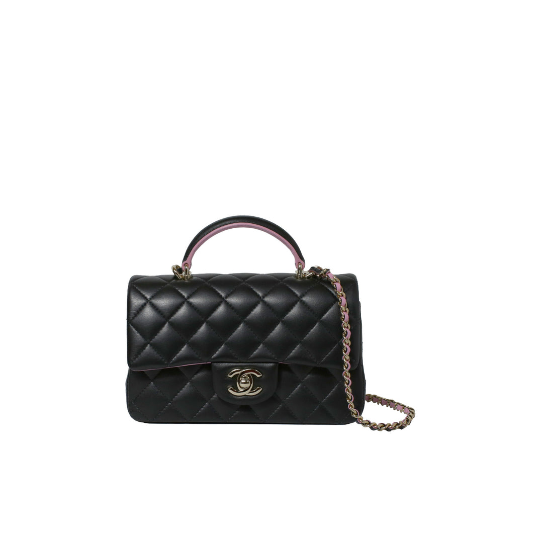 A classic Chanel Mini Rectangular Flap Bag crafted from luxurious black and pink two-tone lambskin leather. Featuring the iconic CC turn lock closure, gold-tone hardware, and a structured top handle