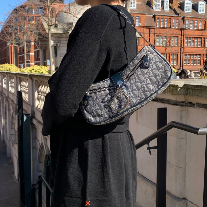 Model carrying the Dior Vintage Oblique Trotter Baguette Bag with D Charm Navy Blue Canvas.