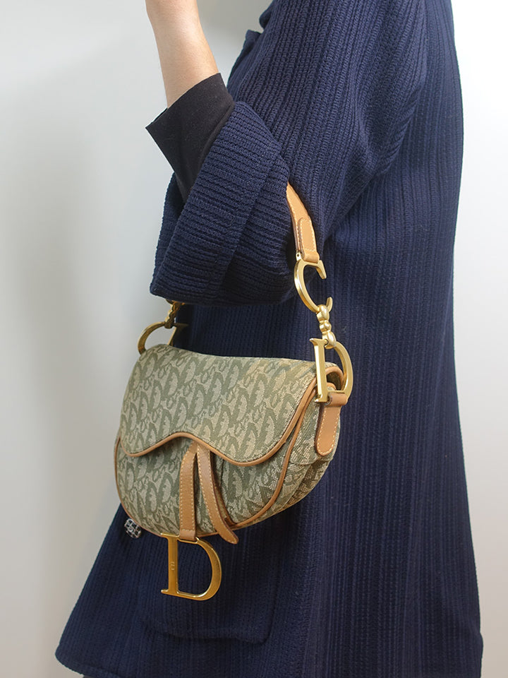 The model is carrying the vintage Dior Saddle Bag by its shoulder strap.