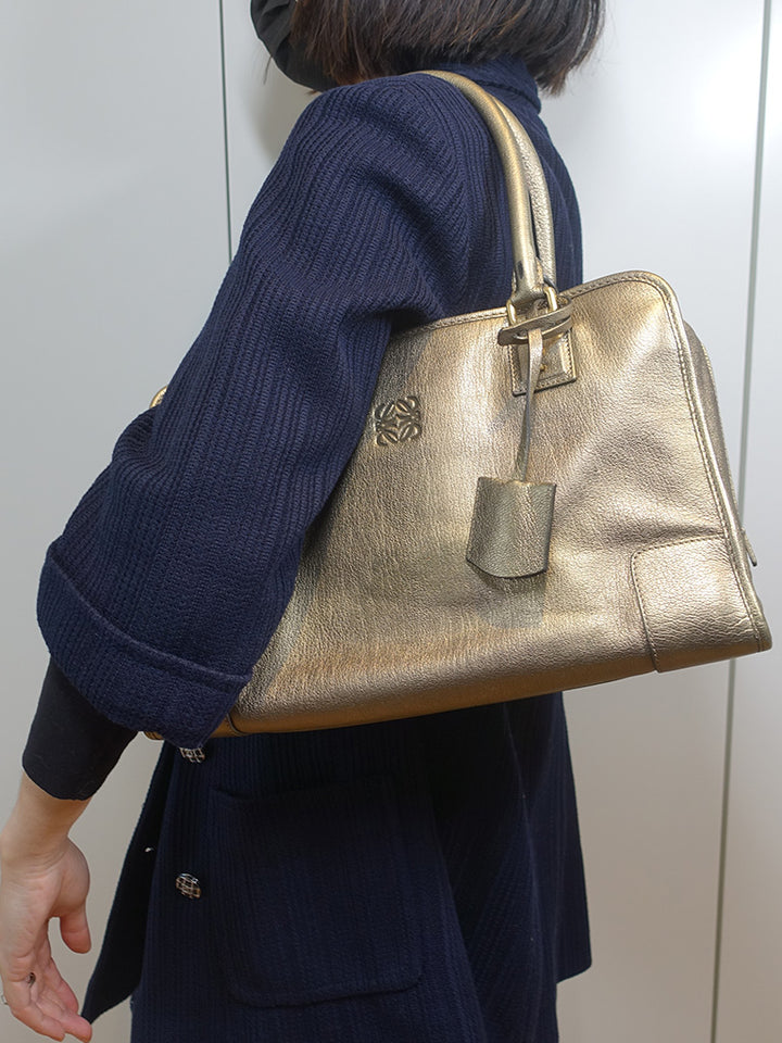 The model is carrying the vintage Loewe Amazona by its shoulder straps.